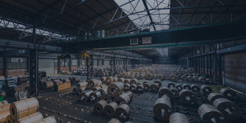 A warehouse of stacked steel coils — the kind of complex cargo flow a WMS, TMS or logistics ERP selection has to handle.